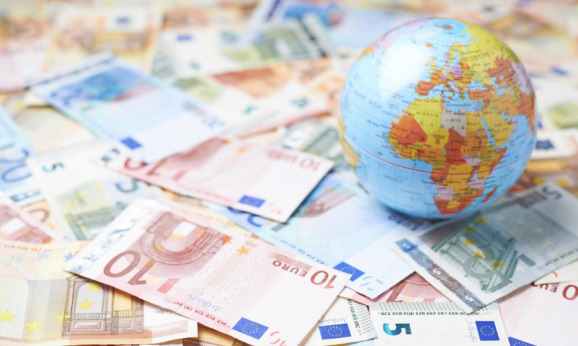 Tiny Earth globe over the surface covered with the multiple bank note bills